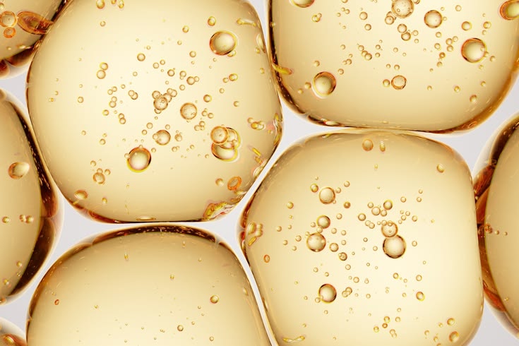 Close-up of golden oil droplets with bubbles on a light background